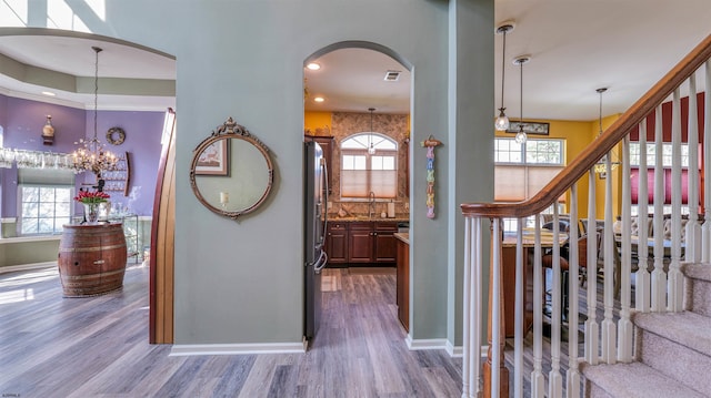 hallway with baseboards, wood finished floors, arched walkways, and stairs