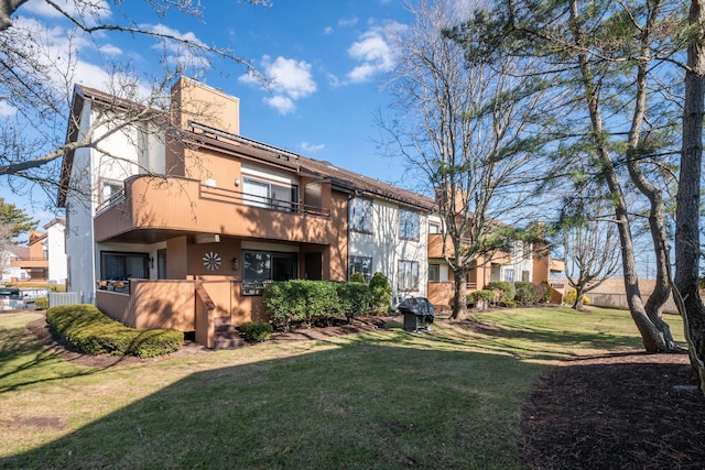 back of property featuring a lawn, stucco siding, and a balcony