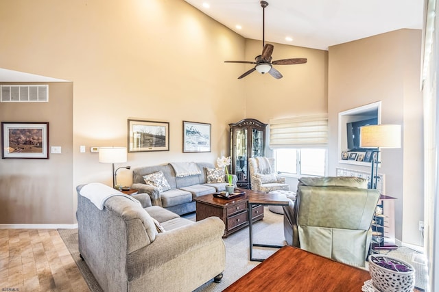 living room featuring wood finished floors, ceiling fan, baseboards, visible vents, and high vaulted ceiling