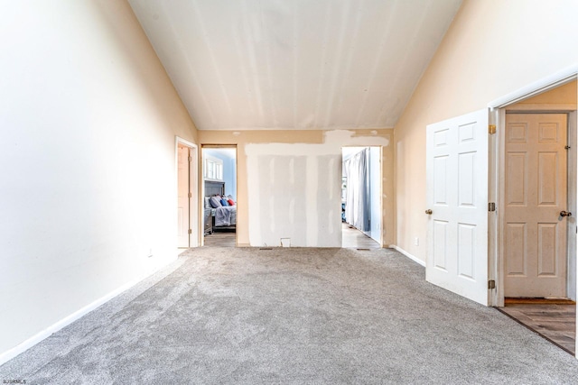 interior space with carpet flooring, baseboards, and lofted ceiling