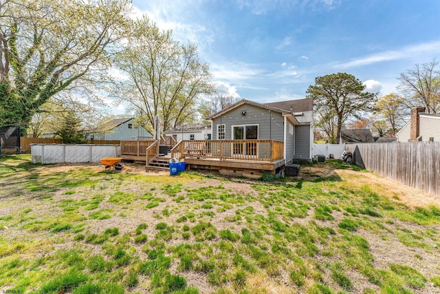 rear view of house featuring a lawn, a wooden deck, and a fenced backyard