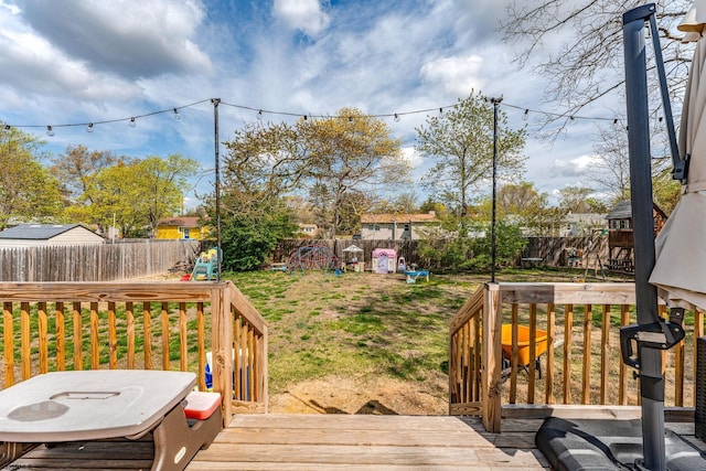 wooden deck with a lawn, a playground, and a fenced backyard