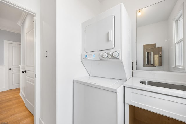 washroom featuring stacked washer and dryer, crown molding, light wood finished floors, and laundry area