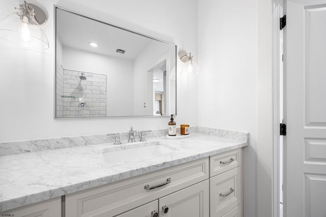 bathroom featuring a tile shower and vanity