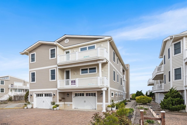 view of front facade with a balcony, driveway, and an attached garage