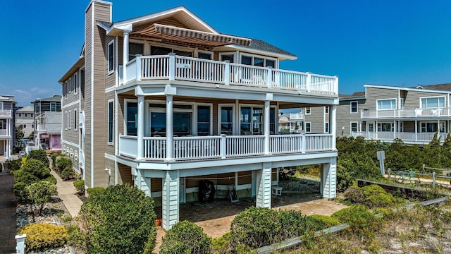 rear view of house with a chimney, a carport, and a balcony