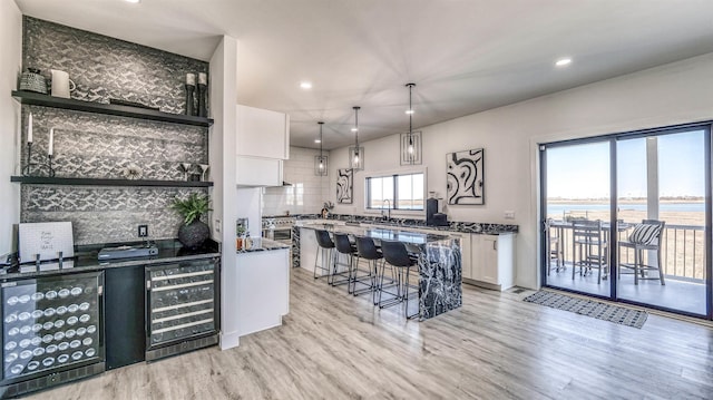 kitchen featuring a breakfast bar area, wine cooler, white cabinetry, and backsplash
