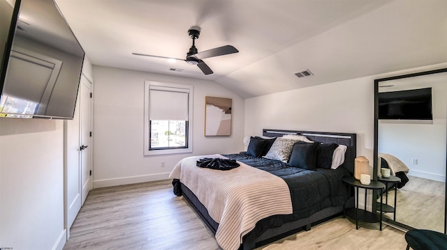 bedroom with lofted ceiling, visible vents, light wood-style flooring, and baseboards