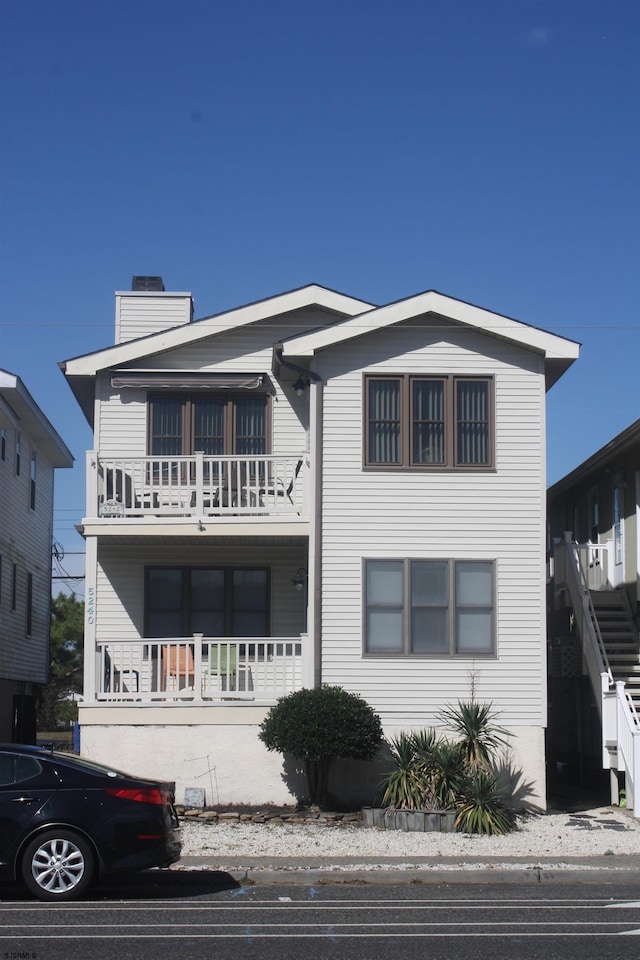 view of front of property featuring a chimney and a balcony