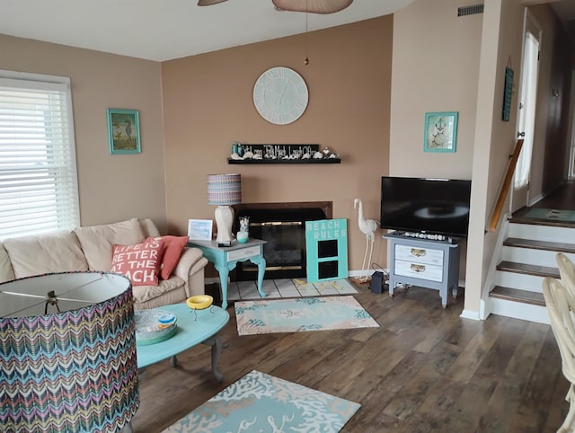 living area with a fireplace with flush hearth, dark wood-style floors, baseboards, a ceiling fan, and stairway