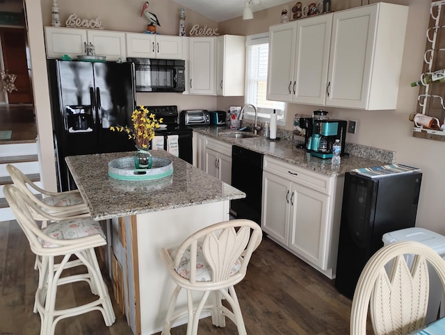 kitchen featuring black appliances, light stone countertops, a sink, and white cabinetry