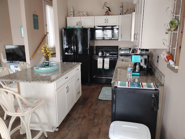 kitchen featuring a kitchen island, dark wood-style floors, white cabinetry, and black appliances