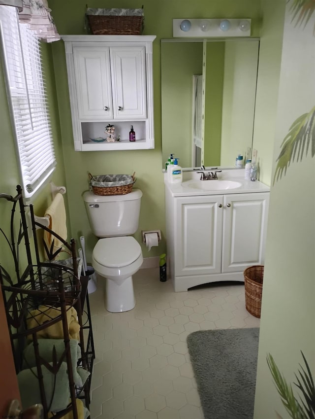 half bathroom featuring tile patterned flooring, baseboards, toilet, and vanity