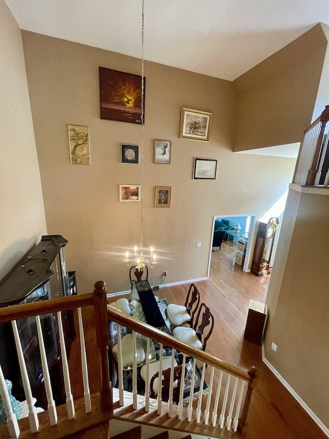 stairs with an inviting chandelier, wood finished floors, and baseboards