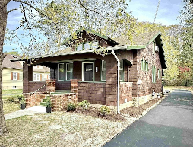 view of front of house featuring a porch, a shingled roof, and driveway