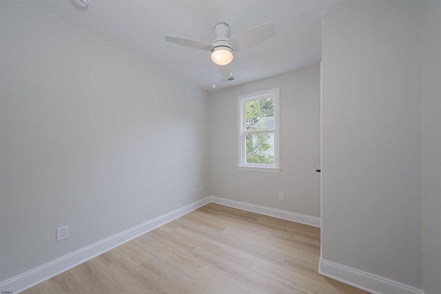 empty room with baseboards, visible vents, a ceiling fan, and light wood finished floors