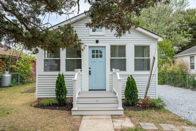 bungalow-style home featuring fence and a front lawn