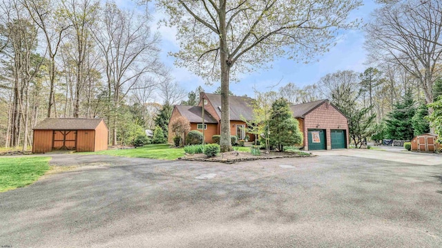 view of front of home with aphalt driveway, a shed, and an outbuilding
