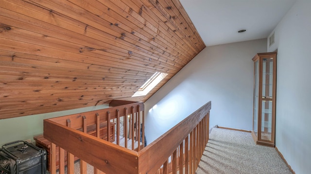 interior space with wood ceiling, carpet flooring, visible vents, baseboards, and lofted ceiling with skylight