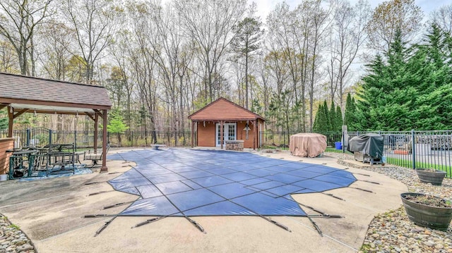 view of swimming pool featuring an outdoor structure, fence private yard, an exterior structure, a fenced in pool, and a patio