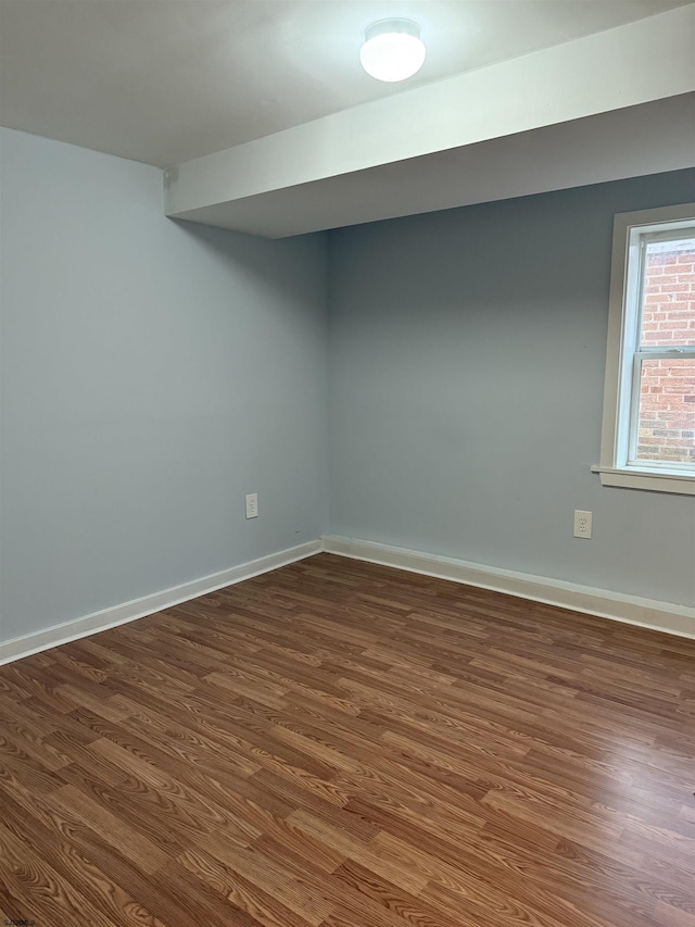 unfurnished room featuring baseboards and dark wood finished floors