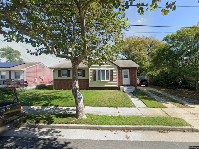 view of front of home featuring fence, a front yard, and brick siding