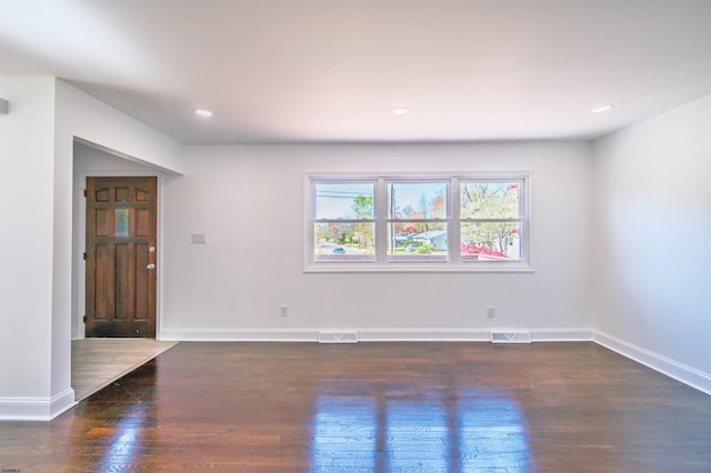 empty room featuring baseboards, visible vents, and wood finished floors
