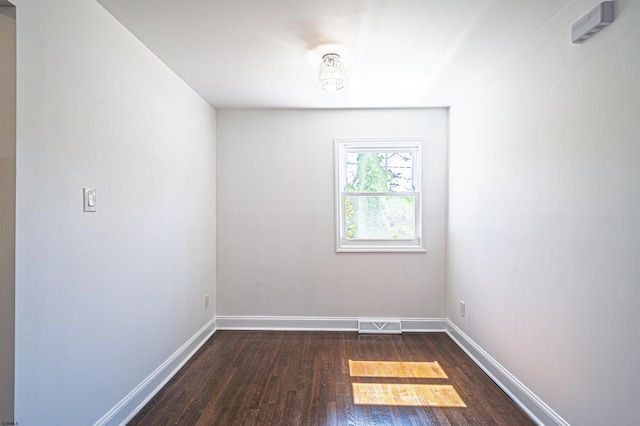 empty room with visible vents, dark wood finished floors, and baseboards