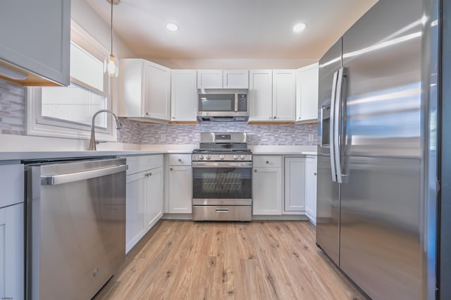kitchen with light wood-style floors, appliances with stainless steel finishes, tasteful backsplash, and light countertops