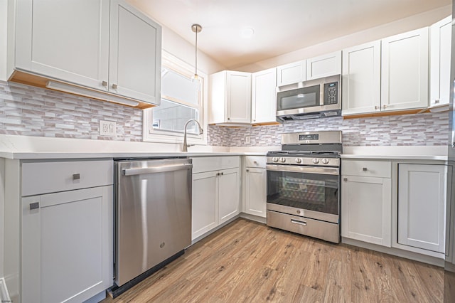 kitchen with a sink, light countertops, light wood-style flooring, and appliances with stainless steel finishes