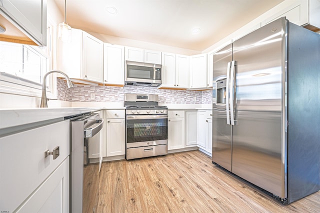 kitchen featuring light wood-type flooring, light countertops, tasteful backsplash, and stainless steel appliances