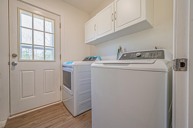 laundry room featuring separate washer and dryer, cabinet space, and wood finished floors