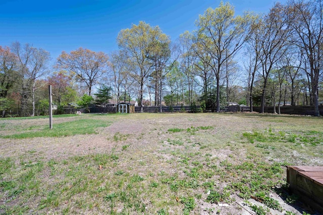 view of yard featuring a storage shed, fence, and an outbuilding