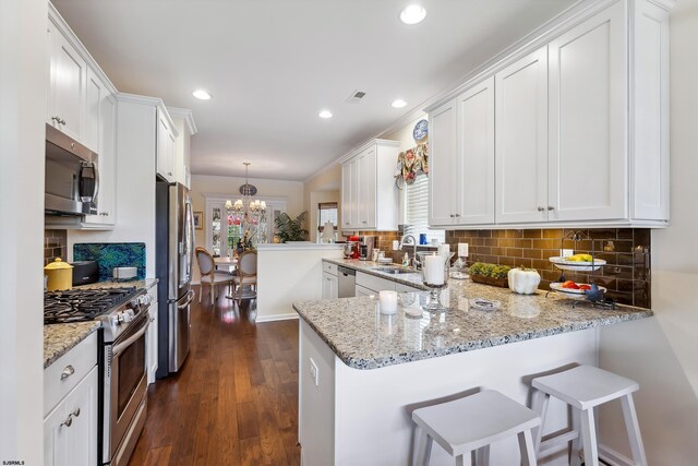 220 Ivy Rd, Egg Harbor Township, NJ 08234 - kitchen featuring appliances with stainless steel finishes, a sink, a peninsula, an inviting chandelier, and white cabinetry