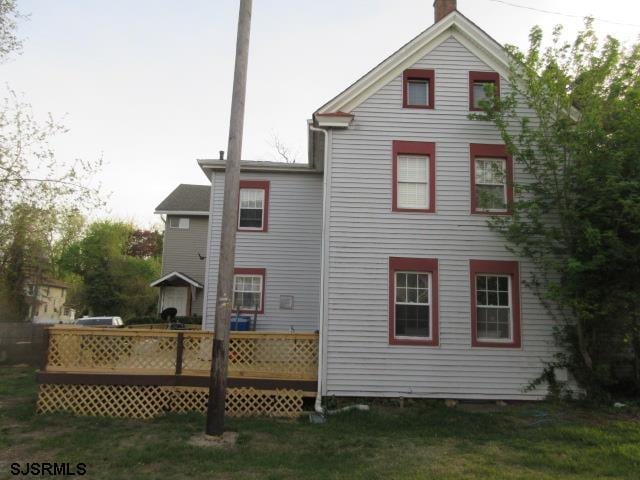back of property with a deck and a chimney