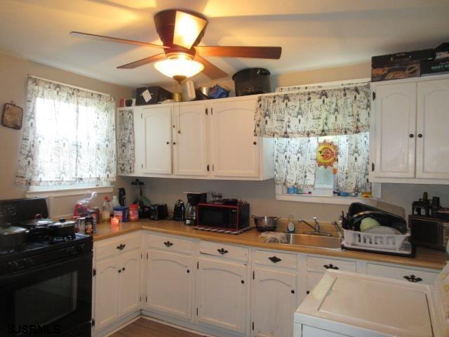kitchen with white cabinets, a sink, and black gas stove