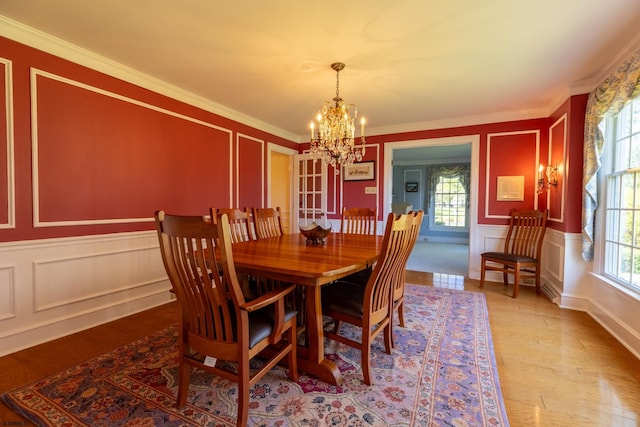 dining space featuring an inviting chandelier, crown molding, a decorative wall, and a healthy amount of sunlight