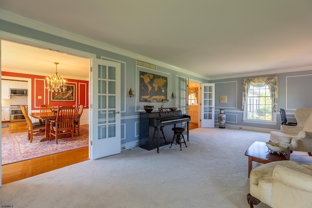 carpeted living area with ornamental molding, french doors, and a chandelier