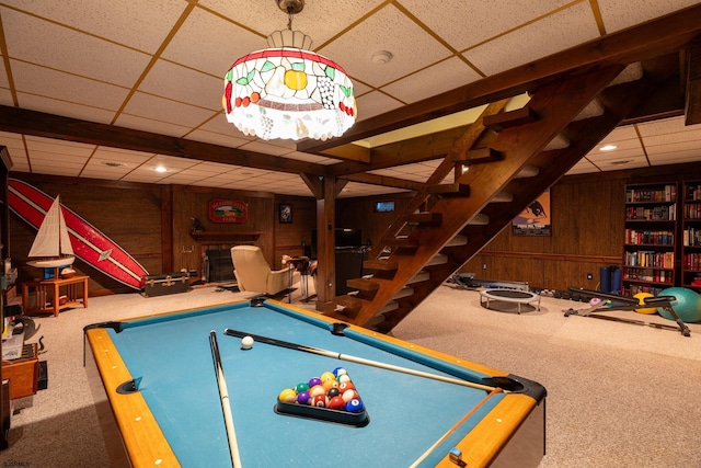 playroom with pool table, a fireplace, wood walls, carpet floors, and a drop ceiling