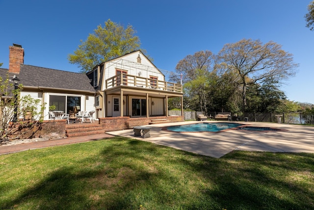 back of property featuring a balcony, a fenced backyard, a fenced in pool, a patio area, and a lawn