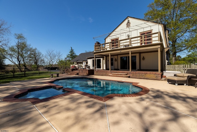 view of swimming pool with a patio, fence, and a pool with connected hot tub