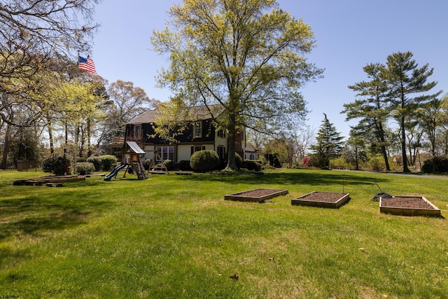 view of yard featuring playground community and a vegetable garden