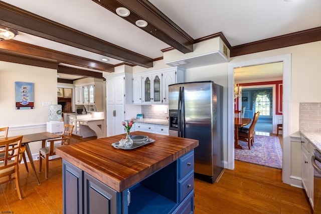 kitchen featuring blue cabinetry, wooden counters, wood finished floors, tasteful backsplash, and stainless steel refrigerator with ice dispenser