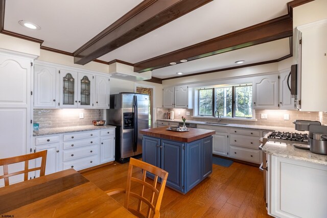 kitchen with a sink, appliances with stainless steel finishes, backsplash, and wooden counters