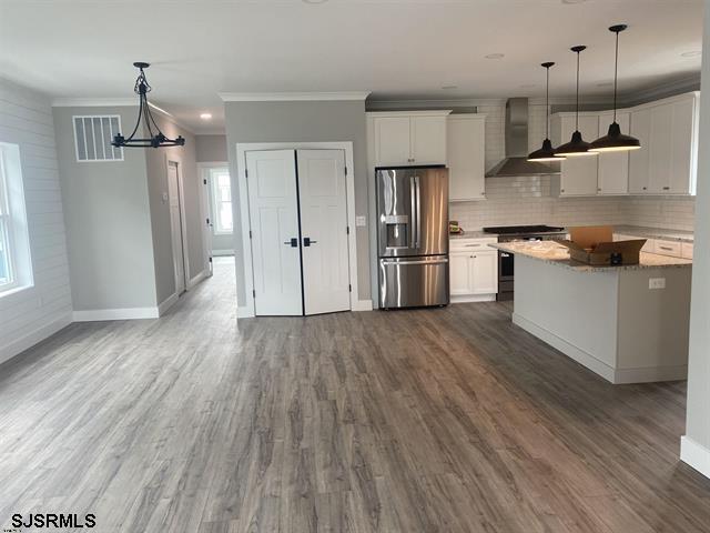 1243 Bay Ave, Ocean City, NJ 08226 - kitchen featuring stainless steel fridge with ice dispenser, range, wall chimney exhaust hood, baseboards, and visible vents