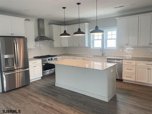 1243 Bay Ave, Ocean City, NJ 08226 - kitchen featuring a sink, wall chimney exhaust hood, stainless steel appliances, tasteful backsplash, and visible vents