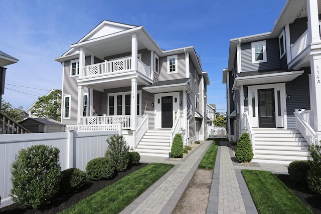 view of front facade featuring covered porch, fence, and a balcony