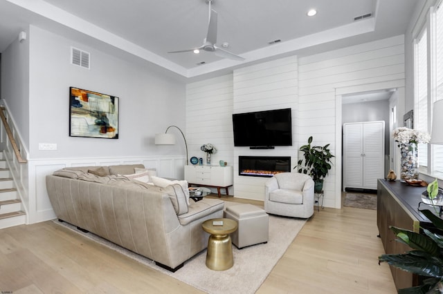 living area featuring visible vents, a raised ceiling, and light wood-style floors