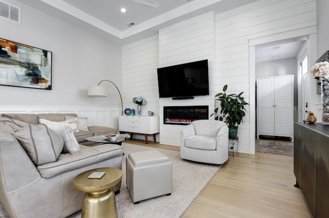 living room with recessed lighting, visible vents, a glass covered fireplace, and light wood-style floors