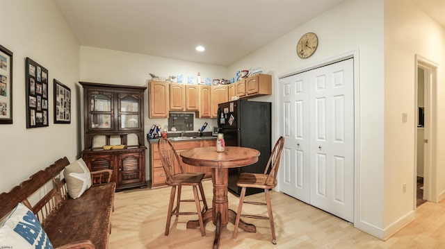 kitchen with dark countertops, freestanding refrigerator, light wood-style floors, light brown cabinets, and recessed lighting